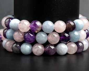 May include: A strand of beads made from aquamarine, amethyst, and rose quartz gemstones. The beads are round and smooth, and they are arranged in a repeating pattern.