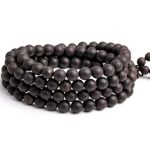 May include: A dark brown wooden beaded bracelet with a knotted tassel. The beads are round and smooth, and the bracelet is made of multiple strands.