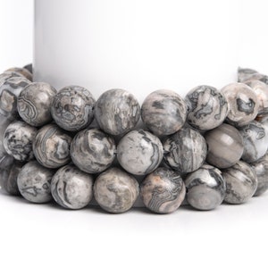 May include: A strand of gray and white marbled stone beads. The beads are round and have a natural, polished finish.