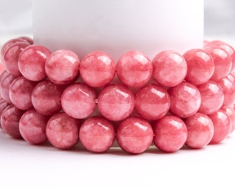 May include: A close-up of a stack of pink gemstone beads. The beads are round and smooth, and they have a slightly translucent appearance.