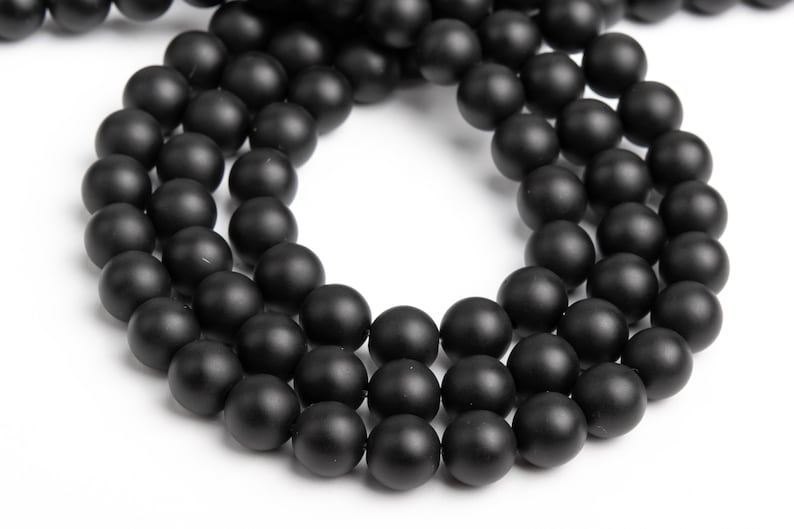 May include: A strand of black matte round beads. The beads are strung together to form a necklace or bracelet.