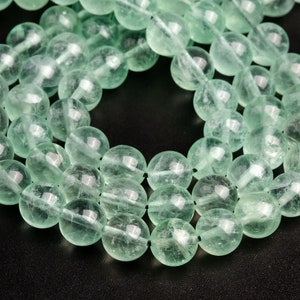 May include: A strand of light green gemstone beads. The beads are round and smooth, and they have a translucent appearance.