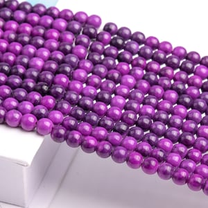 May include: A strand of purple gemstone beads. The beads are round and have a smooth, polished finish.