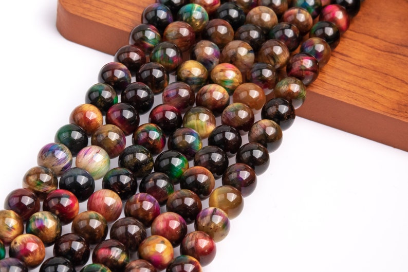 May include: A strand of round, multi-colored tiger's eye beads. The beads are a mix of brown, gold, green, and red with iridescent shimmer.