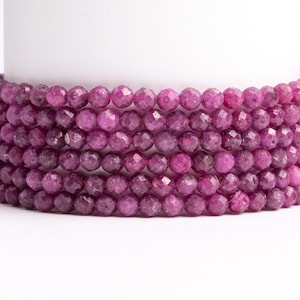 May include: A strand of pink faceted gemstone beads. The beads are round and have a smooth, polished finish.