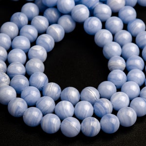 May include: A strand of light blue agate beads with white swirls. The beads are round and smooth, and they are arranged in a circular pattern.