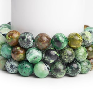 May include: A strand of green and brown gemstone beads. The beads are round and have a mottled appearance.