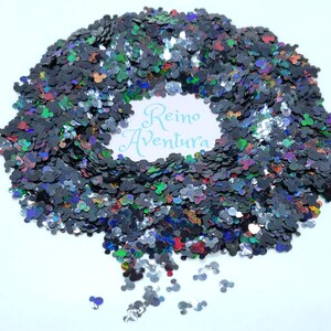 Pode incluir: Glitter preto e iridescente em forma de cabe&ccedil;as do Mickey Mouse. O glitter est&aacute; espalhado sobre uma superf&iacute;cie branca. O texto "Reino Ventura" &eacute; vis&iacute;vel no centro da imagem.