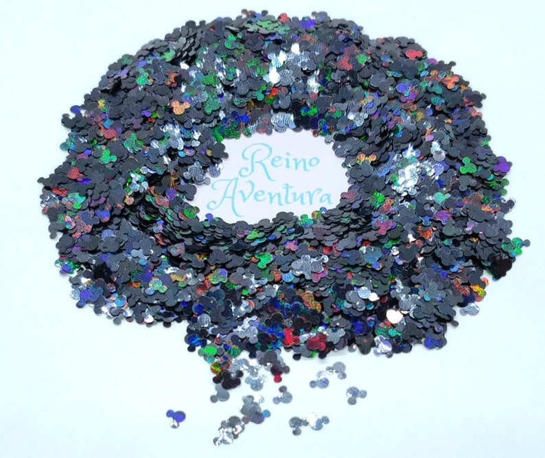 Pode incluir: Glitter preto e iridescente em forma de cabe&ccedil;as do Mickey Mouse. O glitter est&aacute; espalhado sobre uma superf&iacute;cie branca. O texto "Reino Ventura" &eacute; vis&iacute;vel no centro da imagem.