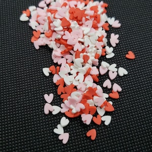 May include: A scattering of small heart-shaped sprinkles in red, pink, and white.