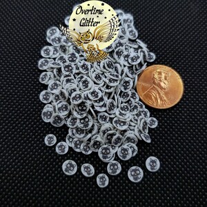 May include: A pile of white and black cat face sprinkles, about the size of a US penny.
