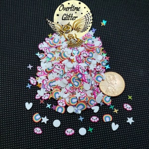 May include: A collection of colorful polymer clay sprinkles in various shapes, including rainbows, clouds, stars, and hearts. The sprinkles are scattered on a black surface, with a penny for size comparison. The text "Overtime Glitter" is visible.