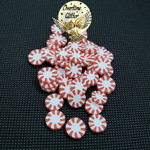 May include: A pile of red and white candy cane-shaped round embellishments. The embellishments are made of polymer clay and are perfect for adding a festive touch to crafts.