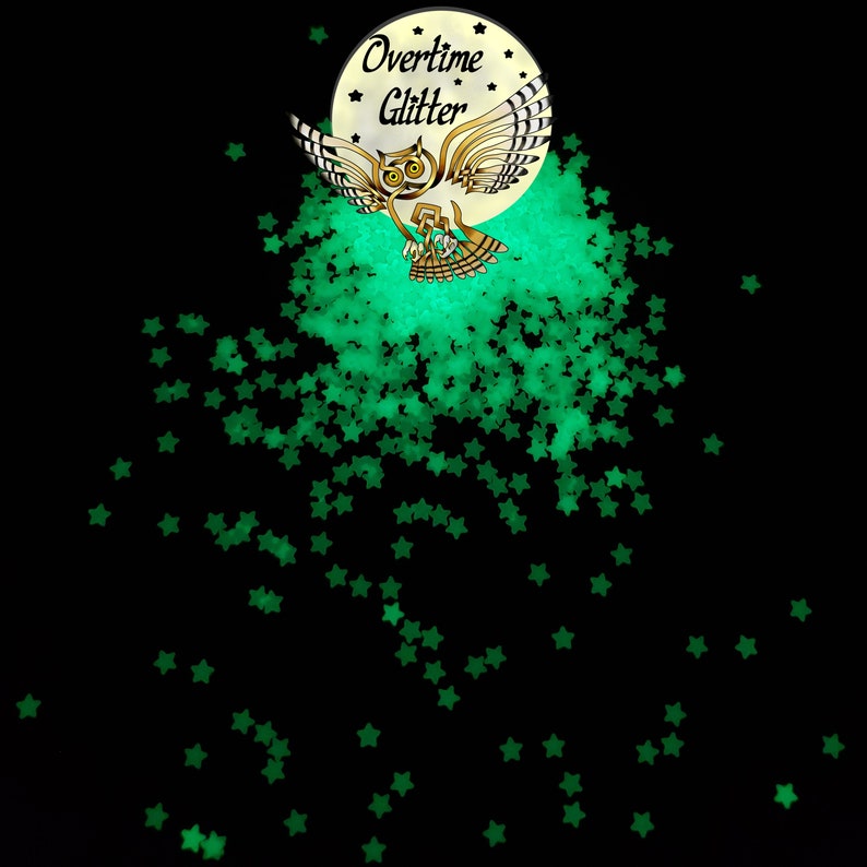 May include: Black background with scattered green star-shaped glitter. A circular logo features an owl with outstretched wings, the text "Overtime Glitter" and a crescent moon. The glitter appears to glow.