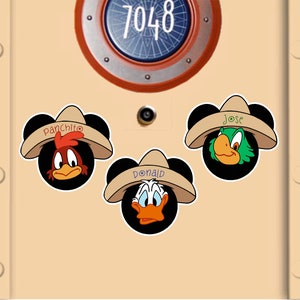 May include: Three cartoon character stickers with Mickey Mouse ears wearing sombreros. The characters are Panchito, Donald, and Jose. The background is a light tan door with a circular porthole and the number 7048.