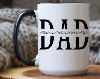 Może przedstawiać: Biały kubek ceramiczny z czarnym uchwytem i czarnym rantem. Kubek ma napis "DAD" wydrukowany dużymi czarnymi literami, a pod nim mniejszą czcionką imiona "Kristin", "Emily", "Liam" i "Kayla".