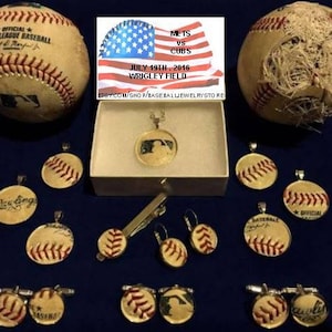 May include: A collection of baseball-themed jewelry, including earrings, cufflinks, and pendants. The jewelry features baseballs, bats, and other baseball-related designs. The jewelry is displayed on a white surface with a baseball game poster in the background.