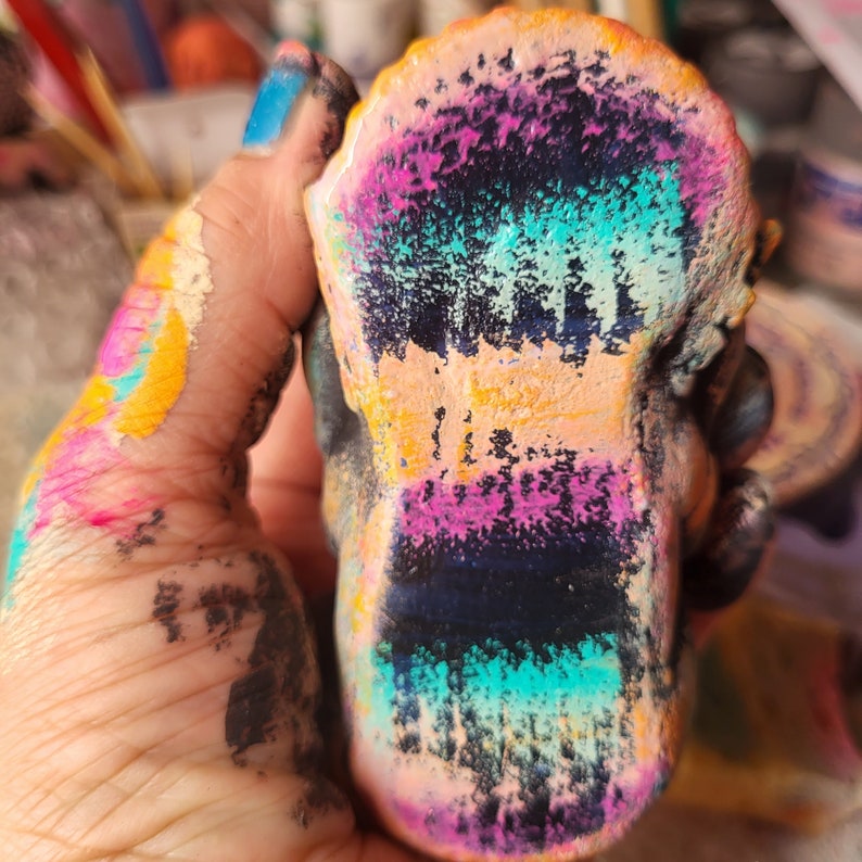 May include: A colourful, hand-painted ceramic sculpture with a textured surface. The sculpture is painted in shades of pink, blue, green, yellow, and black.