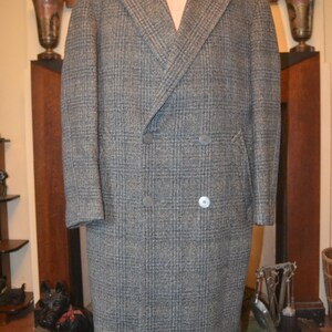 May include: A gray and blue plaid double-breasted overcoat. The coat has a notched lapel, two rows of buttons, and two front pockets. The coat is displayed on a mannequin.