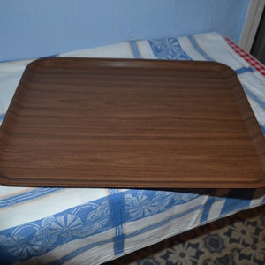 May include: A brown wooden serving tray with a slightly rounded rectangular shape.