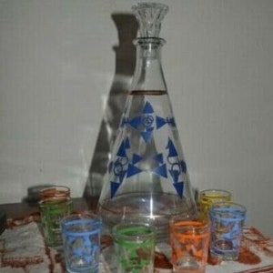 Peut inclure: Un ensemble de carafes en verre transparent avec des motifs géométriques bleus et dorés. L'ensemble comprend une grande carafe et six petits verres à liqueur.
