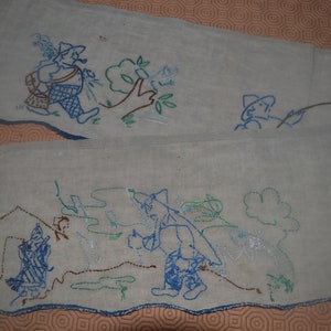 May include: Two embroidered fabric panels with a scalloped edge. The panels feature a whimsical design of people fishing in a forest setting. The embroidery is done in shades of blue, green, and brown.