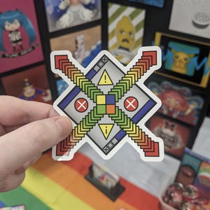 May include: A die-cut sticker featuring a diamond-shaped design with a central square divided into four smaller coloured squares. Two crossed bars with repeating chevron patterns extend from the centre, accented by yellow warning triangles and red circles with white X symbols.