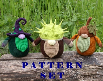 May include: Three handmade crochet gnomes in a natural setting. One gnome wears a purple witch hat, another has a spiky green head, and the third is acorn-shaped. The text "PATTERN SET" is visible on the log.
