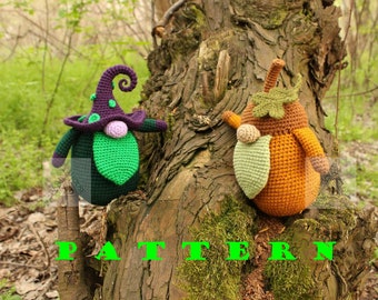 May include: Two crocheted gnomes, one with a purple hat and green beard, the other with an orange pumpkin body and green leaves, sitting on a tree trunk with the word "PATTERN" written in green letters below them.