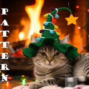 May include: A tabby cat wearing a green crocheted Christmas tree hat with colourful bulb ornaments and a yellow star. The word "PATTERN" is written vertically on the left side of the image. The background features a fireplace with a warm glow.