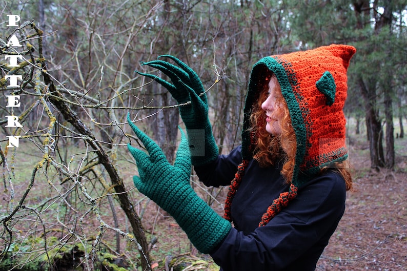 May include: A crochet set featuring a bright orange hooded cowl with dark green trim and pointed ear-like accents, paired with long dark green gloves that have elongated, claw-like fingers. The word PATTERN is printed vertically in white on the left.