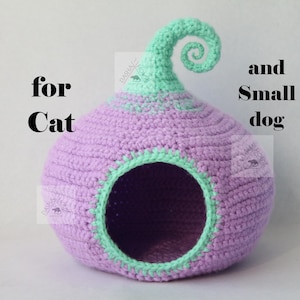 May include: A handmade crochet pet bed in a bulbous shape, primarily lavender with mint green accents. The bed has a circular opening and a decorative swirl at the top. Text on the image reads "PATTERN for Cat and Small dog."