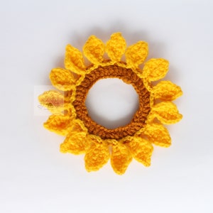 May include: A handmade crochet sunflower hair tie. The hair accessory features a bright yellow flower with a brown center and yellow petals. The sunflower is a cheerful and summery accessory.