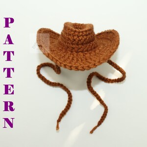 Puede incluir: Un sombrero de vaquero marr&oacute;n tejido a ganchillo con ala ancha y cord&oacute;n. La palabra "PATTERN" se muestra verticalmente en letras moradas en el lado izquierdo de la imagen. El sombrero est&aacute; hecho de hilo texturizado.