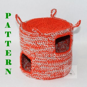 May include: A crocheted orange and grey cylindrical pet house with two openings. The house has three loops on top.