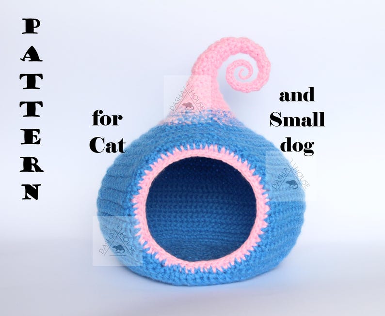 May include: A blue and pink crocheted pet bed with a round opening. The bed has a spiral design on top and the text "PATTERN for Cat and Small dog".