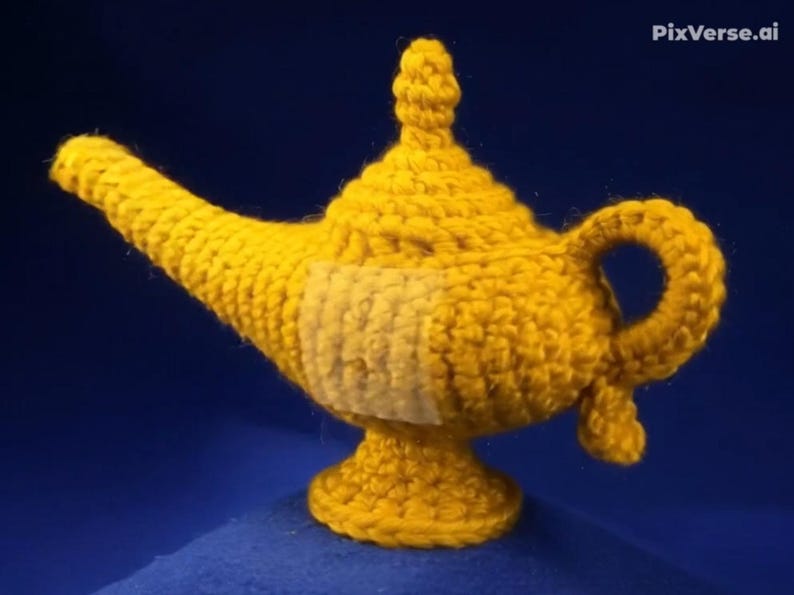 K&ouml;nnte beinhalten: Eine handgefertigte, gelbe H&auml;kellampe mit Ausguss, Griff und Sockel. Die Lampe hat ein strukturiertes, gewebtes Design und einen hellfarbigen Aufn&auml;her an der Seite. Der Hintergrund ist einfarbig dunkelblau.