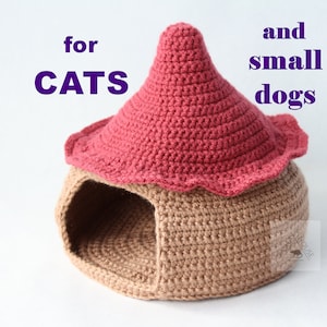 Könnte beinhalten: Ein handgefertigtes Häkel-Haustierhaus in Pilzform. Das Haus ist beige mit rotem Dach und gewelltem Rand. Der Text auf dem Bild lautet "Pattern for cats and small dogs."