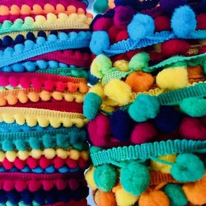 Puede incluir: Una colección de ribetes de pompón de colores con varios colores y tamaños. El ribete está hecho de pompones suaves y esponjosos unidos a una cinta.