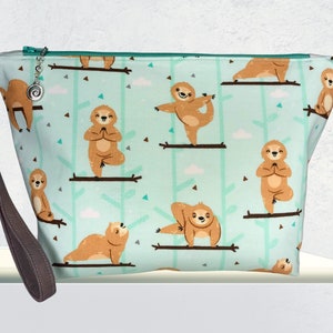 May include: A teal blue zippered pouch with a brown strap. The pouch has a repeating pattern of sloths doing yoga poses on branches.