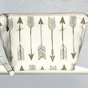 May include: A white canvas zippered pouch with a green arrow print. The pouch has a zipper closure and a detachable strap.