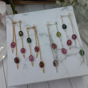 Puede incluir: Cuatro pares de pendientes colgantes con múltiples cuentas en tonos rosa, verde y negro. Los pendientes están hechos con cadenas doradas y plateadas.