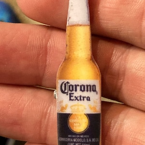 May include: A green glass bottle of Corona Extra beer with a yellow cap. The bottle is labeled with the Corona Extra logo and text in Spanish and English. The bottle is 330 ml.