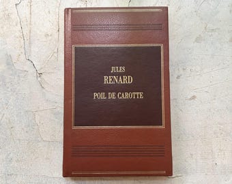 Op de afbeelding: Een vintage hardcover boek met een bruine leren kaft. Het boek heeft de titel "Jules Renard" en "Poil de Carotte" in gouden letters op een donkerbruin rechthoekig paneel. Het boek heeft een gouden rand en staat tegen een neutrale achtergrond.