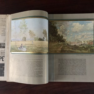 May include: An open book with two paintings of landscapes. The left page shows a painting of a field with trees and a couple sitting on a blanket. The right page shows a painting of a river with trees and a town in the distance.