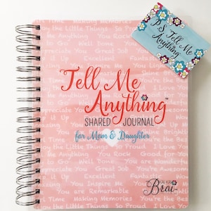 May include: A pink and white spiral bound journal with the words "Tell Me Anything" in red. The journal is a shared journal for a mom and daughter. The cover is decorated with a pattern of hearts and the words "Tell Me Anything" repeated in a smaller font. The journal is sitting on a white surface.