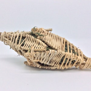Puede incluir: Una cesta tejida en forma de estrella, hecha de juncos de color marr&oacute;n claro. La cesta est&aacute; llena de follaje verde, creando una apariencia natural y texturizada. El dise&ntilde;o es intrincado, con los juncos cuidadosamente entrelazados.