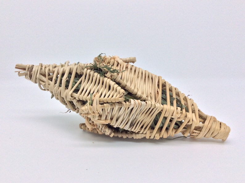 Puede incluir: Una cesta tejida en forma de estrella, hecha de juncos de color marr&oacute;n claro. La cesta est&aacute; llena de follaje verde, creando una apariencia natural y texturizada. El dise&ntilde;o es intrincado, con los juncos cuidadosamente entrelazados.