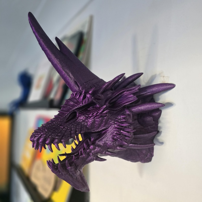 May include: Purple dragon head wall sculpture with a sharp horn and detailed scales.