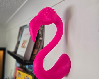 May include: A bright pink flamingo-shaped wall hook. The hook is made of plastic and has a smooth, glossy finish.